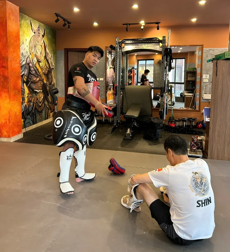 Coach correcting a student's kicking technique, the main defence against muay thai injuries for beginners