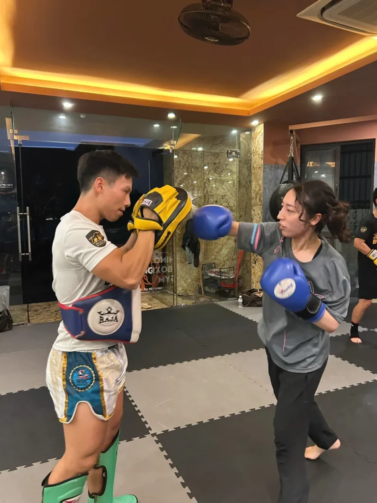 Coach holding pads for a student during a Combat Fit session