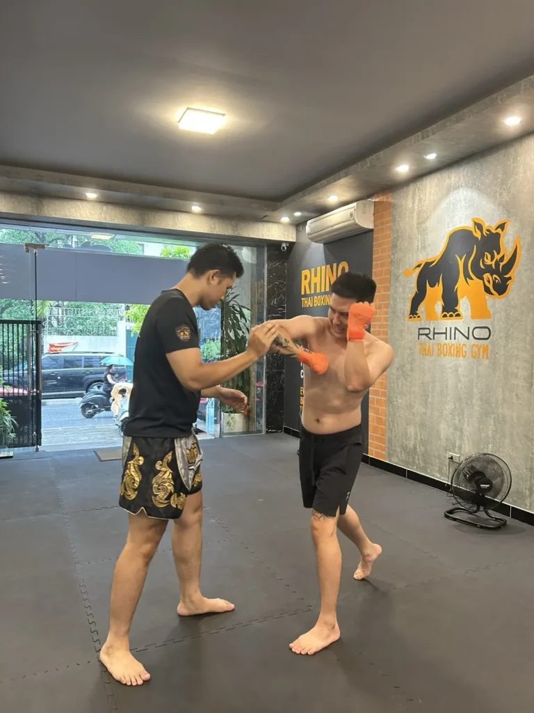 Coach holding pads for a member during a one-to-one Muay Thai session