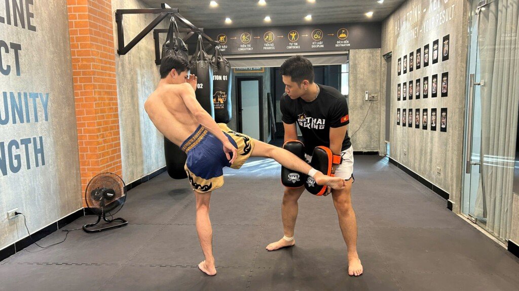 HLV RHINO giữ đích hướng dẫn cách đá low kick cho học viên trong buổi tập Muay Thái tại Tây Hồ