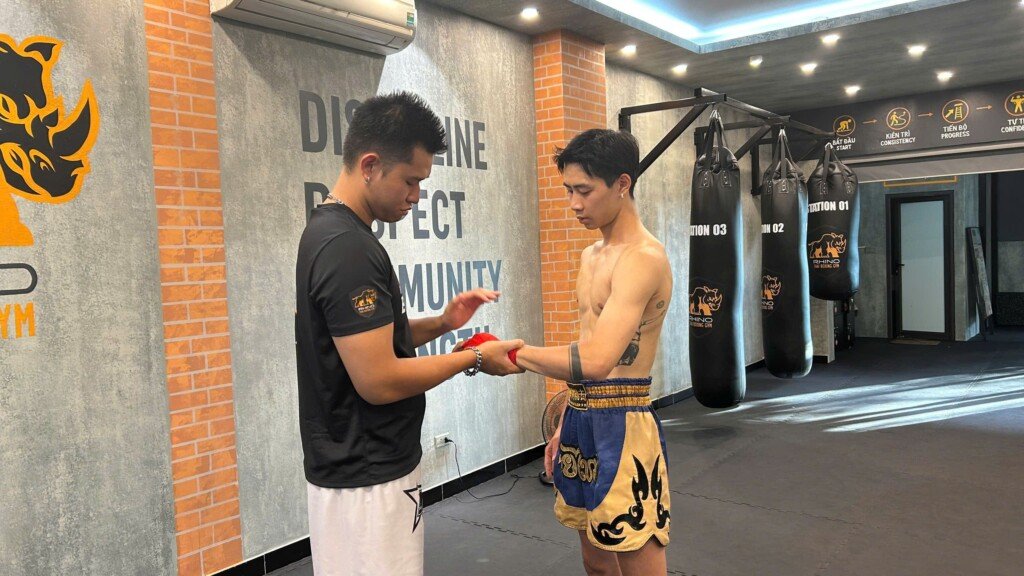 A RHINO coach checks a student's completed muay thai hand wraps before gloves go on
